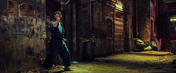 Movie still from “Ip Man 4: The Finale” (2019), directed by Wilson Yip – A man in a blue shirt is in the street; Wide shot, Low angle