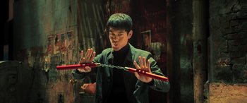 Movie still from “Ip Man 4: The Finale” (2019), directed by Wilson Yip – A man holding a pair of red sticks in front of him; Medium shot, Low angle
