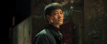 Movie still from “Ip Man 4: The Finale” (2019), directed by Wilson Yip – A man with a black shirt is looking to his left; Close Up shot, Low angle