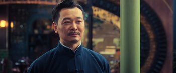 Movie still from “Ip Man 4: The Finale” (2019), directed by Wilson Yip – A person wearing a suit and tie; Close Up shot, Over the shoulder angle