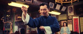 Movie still from “Ip Man 4: The Finale” (2019), directed by Wilson Yip – A man in a blue and white outfit holding something up; Medium shot, Low angle