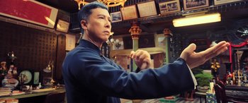Movie still from “Ip Man 4: The Finale” (2019), directed by Wilson Yip – A man in a blue jacket is holding something in his hand; Medium shot, Low angle