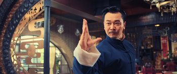 Movie still from “Ip Man 4: The Finale” (2019), directed by Wilson Yip – A man holding up his hand in a sign language; Medium shot, Low angle