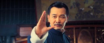 Movie still from “Ip Man 4: The Finale” (2019), directed by Wilson Yip – A man in a blue shirt is holding up his hand; Close Up shot, Low angle