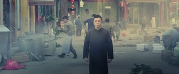 Movie still from “Ip Man 4: The Finale” (2019), directed by Wilson Yip – A man in a priest's outfit standing in the middle of the street; Medium shot, Low angle