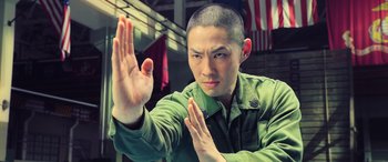 Movie still from “Ip Man 4: The Finale” (2019), directed by Wilson Yip – A man with a shaved head is holding his hands up; Close Up shot, Low angle