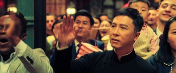 Movie still from “Ip Man 4: The Finale” (2019), directed by Wilson Yip – A group of people standing in front of a building; Close Up shot, Low angle