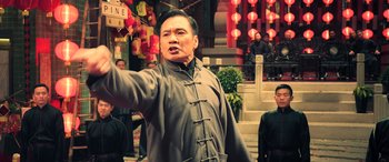 Movie still from “Ip Man 4: The Finale” (2019), directed by Wilson Yip – An older man in a gray jacket is waving; Medium shot, Low angle