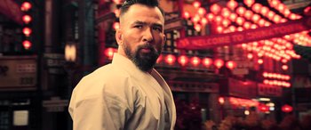 Movie still from “Ip Man 4: The Finale” (2019), directed by Wilson Yip – A man with a beard is standing in front of lights; Close Up shot, Low angle