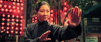 Movie still from “Ip Man 4: The Finale” (2019), directed by Wilson Yip – A woman in a black shirt is practicing martial arts in front of red lights; Medium shot, Low angle