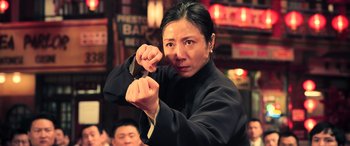 Movie still from “Ip Man 4: The Finale” (2019), directed by Wilson Yip – A woman in a black shirt is holding a knife; Medium shot, Low angle