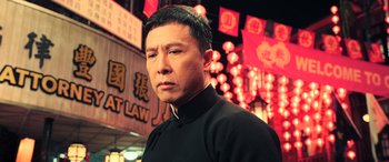 Movie still from “Ip Man 4: The Finale” (2019), directed by Wilson Yip – A man standing in front of a building in the dark; Close Up shot, Low angle