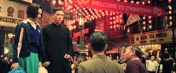 Movie still from “Ip Man 4: The Finale” (2019), directed by Wilson Yip – A man in a black shirt is talking to a man in a tan suit; Medium shot, Low angle