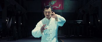 Movie still from “Ip Man 4: The Finale” (2019), directed by Wilson Yip – A man in a white shirt is doing a hand sign; Medium shot, Low angle
