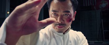 Movie still from “Ip Man 4: The Finale” (2019), directed by Wilson Yip – A man with a bruised face and a white shirt; Close Up shot, Low angle