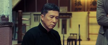Movie still from “Ip Man 4: The Finale” (2019), directed by Wilson Yip – A man in a black shirt is looking at the camera; Close Up shot, Low angle