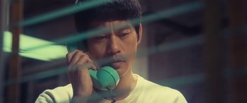 Movie still from “Ip Man 4: The Finale” (2019), directed by Wilson Yip – A man with headphones on talking on a phone; Close Up shot, High angle
