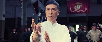 Movie still from “Ip Man 4: The Finale” (2019), directed by Wilson Yip – A man clapping his hands while wearing a white shirt; Close Up shot, Low angle