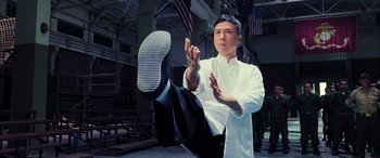Movie still from “Ip Man 4: The Finale” (2019), directed by Wilson Yip – A man in white shirt and black pants doing a karate kick; Medium shot, Low angle