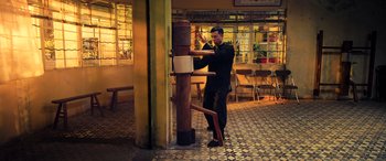 Movie still from “Ip Man 4: The Finale” (2019), directed by Wilson Yip – A man in a black shirt is doing a kick stand; Wide shot, Low angle