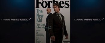 Movie still from “Iron Man” (2008), directed by Jon Favreau – A man in a suit and tie standing next to another man in a suit and tie; Medium shot, Overhead angle