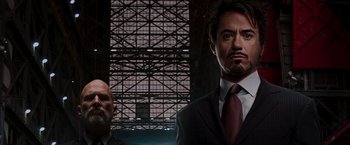 Movie still from “Iron Man” (2008), directed by Jon Favreau – A man in a suit and tie standing next to another man in a suit and tie; Close Up shot, Low angle