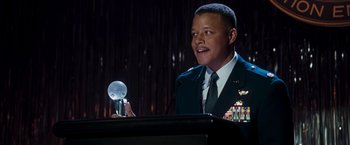 Movie still from “Iron Man” (2008), directed by Jon Favreau – A man in a military uniform speaking at a podium; Close Up shot, Low angle
