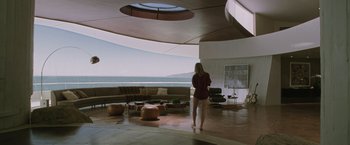 Movie still from “Iron Man” (2008), directed by Jon Favreau – A woman standing in a room with a view of the ocean; Wide shot, High angle