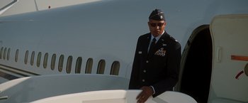 Movie still from “Iron Man” (2008), directed by Jon Favreau – A man in a military uniform standing next to an airplane; Medium shot, Low angle