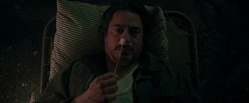 Movie still from “Iron Man” (2008), directed by Jon Favreau – A man laying in a bed with his nose on a toothpick; Close Up shot, High angle