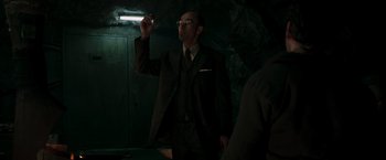 Movie still from “Iron Man” (2008), directed by Jon Favreau – A man in a suit and tie holding a glass; Medium shot, Low angle