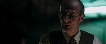 Movie still from “Iron Man” (2008), directed by Jon Favreau – An older bald man wearing glasses and a tie; Close Up shot, Low angle