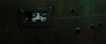 Movie still from “Iron Man” (2008), directed by Jon Favreau – A man looking through a hole in a wall; Extreme Close Up shot, Low angle
