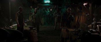 Movie still from “Iron Man” (2008), directed by Jon Favreau – A group of people standing in a room; Wide shot, Over the shoulder angle