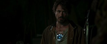 Movie still from “Iron Man” (2008), directed by Jon Favreau – A person wearing a necklace; Close Up shot, Over the shoulder angle