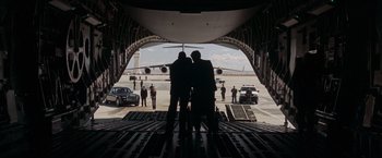 Movie still from “Iron Man” (2008), directed by Jon Favreau – Two men standing on the back of an airplane; Wide shot, Low angle