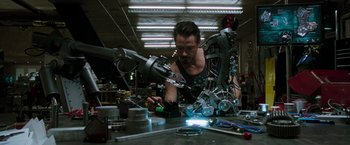 Movie still from “Iron Man” (2008), directed by Jon Favreau – A man working in an industrial setting with a lot of tools; Medium shot, Low angle