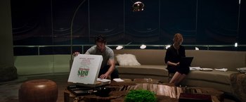 Movie still from “Iron Man” (2008), directed by Jon Favreau – A man opening a pizza box in a living room; Medium shot, High angle