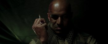 Movie still from “Iron Man” (2008), directed by Jon Favreau – A man with a blood covered face holding up a cigarette; Close Up shot, Low angle