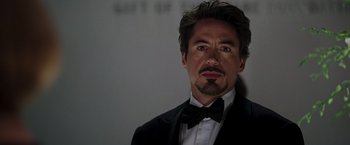 Movie still from “Iron Man” (2008), directed by Jon Favreau – A person wearing a suit and a bow tie; Close Up shot, Over the shoulder angle