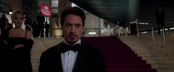 Movie still from “Iron Man” (2008), directed by Jon Favreau – A person wearing a suit and a bow tie; Medium shot, Low angle