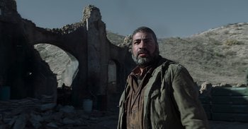 Movie still from “Iron Man” (2008), directed by Jon Favreau – A man standing in front of an abandoned building; Medium shot, Low angle