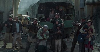 Movie still from “Iron Man” (2008), directed by Jon Favreau – A group of people standing in front of an army vehicle; Wide shot, Low angle