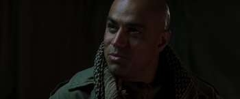 Movie still from “Iron Man” (2008), directed by Jon Favreau – A bald man wearing a green jacket and a brown scarf; Close Up shot, Low angle