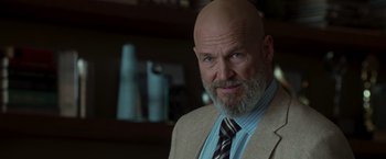 Movie still from “Iron Man” (2008), directed by Jon Favreau – A man with a beard wearing a suit and tie; Close Up shot, Low angle