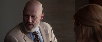 Movie still from “Iron Man” (2008), directed by Jon Favreau – A man with a bald head wearing a suit and tie; Close Up shot, Low angle