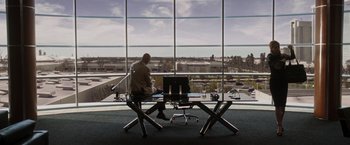 Movie still from “Iron Man” (2008), directed by Jon Favreau – A man sitting at a desk in front of an open window; Wide shot, High angle