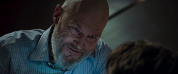 Movie still from “Iron Man” (2008), directed by Jon Favreau – An older man with a beard and a blue striped shirt; Close Up shot, Over the shoulder angle