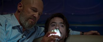 Movie still from “Iron Man” (2008), directed by Jon Favreau – A man holding a cell phone up to his face; Close Up shot, Over the shoulder angle