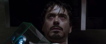 Movie still from “Iron Man” (2008), directed by Jon Favreau – A person holding a glass object; Close Up shot, Low angle